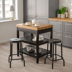 a kitchen island with two stools and a cutting board on the bottom shelf in front of it