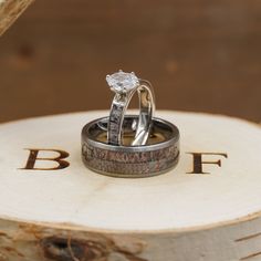 two wedding rings sitting on top of each other in front of a tree stump with the initials b f