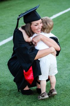 a woman and child hug each other while wearing graduation caps and gowns on the field