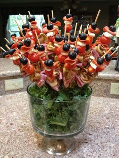 many skewered meats and vegetables in a glass bowl on a counter top