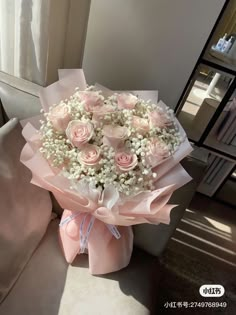 a bouquet of pink roses and baby's breath is sitting on a couch in front of a window