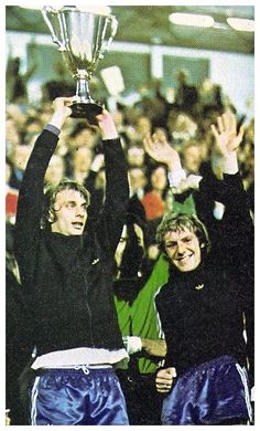 two people holding up a trophy in front of a crowd