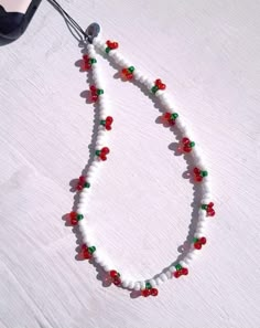 a beaded necklace with red, green and white beads is hanging from a hook