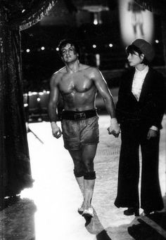 an old black and white photo of a shirtless man holding hands with a woman