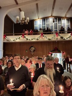 a group of people standing around each other holding candles