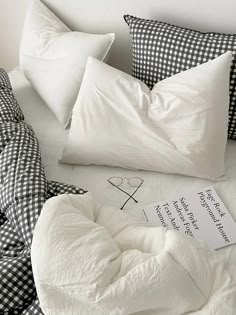 a bed with black and white checkered sheets, pillows and a note on it