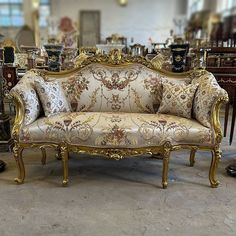 an ornately decorated couch sitting in a room filled with antique furniture and other antiques