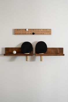 two ping pong paddles mounted to the side of a wooden rack on a wall