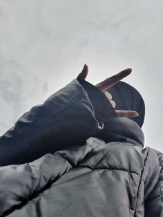 a person wearing a jacket and hat with their hands in the air