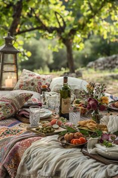 a table with food and drinks on it in the middle of a field near a tree