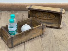 two wooden boxes with bottles in them sitting on the floor next to each other,