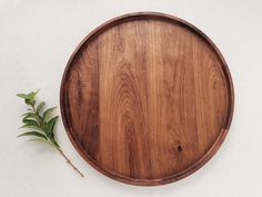 a wooden plate with some green leaves on the side and a white wall behind it