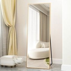 a large mirror sitting in the middle of a room next to a white couch and chair