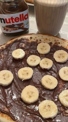 a chocolate dessert with bananas and nutella toppings on the table next to a jar of nutella