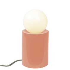 a pink table lamp with a white ball on it's base and a light bulb plugged in