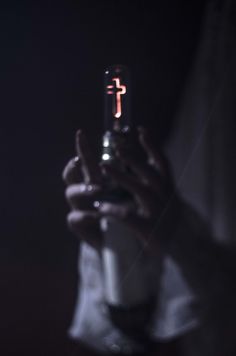 a person holding a cell phone in their hand with a cross on the back of it