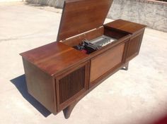 an old fashioned record player sitting on top of a wooden cabinet with its lid open