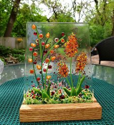 a glass vase filled with plants on top of a table