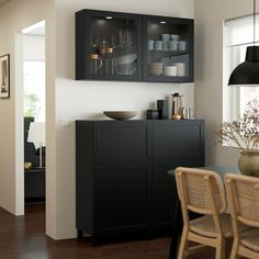 a dining room table and chairs in front of a black cabinet