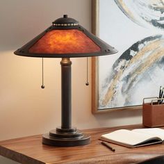 a lamp that is sitting on top of a desk next to a book and pen