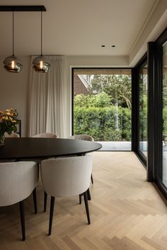 an elegant dining room with wood floors and glass doors that lead out to the backyard