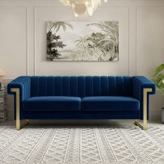 a living room with a blue velvet couch and white rugs on the floor next to a painting