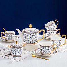 a white table topped with lots of blue and white dishes covered in gold trimmings