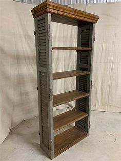 an old wooden bookcase with shutters on the front and bottom shelves is shown