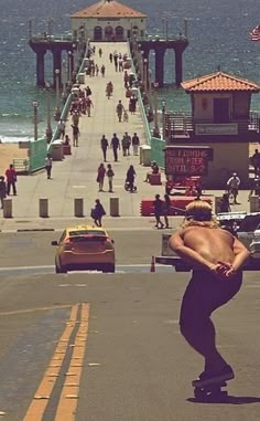 a man riding a skateboard down the middle of a street next to a pier