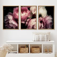 two pink flowers are hanging on the wall next to a white bench with baskets underneath them