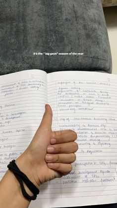 a person holding up a book with writing on it and giving the thumbs up sign