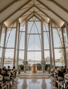 the inside of a church with large windows and white flowers on the pews at the alter