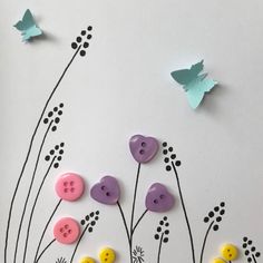 paper butterflies and flowers on a white background with blue, pink, yellow and purple buttons