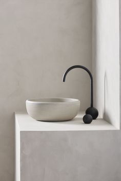 a white bowl sitting on top of a counter next to a black faucet