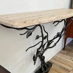 a wooden shelf with metal branches and leaves on the top, against a white wall