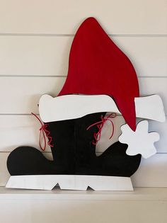 a red and white santa hat sitting on top of a shoe shaped cardboard cutout