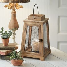 a wooden lantern sitting on top of a table next to some books and a plant