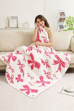 a woman sitting on a couch with a pink and white blanket