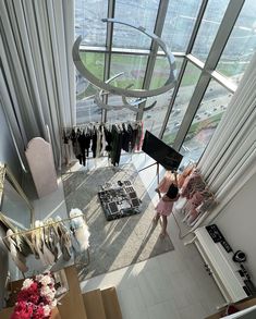 two women looking down at clothes on racks in a room with high ceilings and large windows