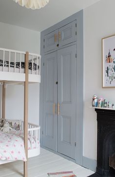 a bedroom with a bunk bed and blue cupboards next to a white fire place