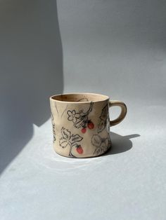 a coffee cup sitting on top of a white table next to a shadow from the wall