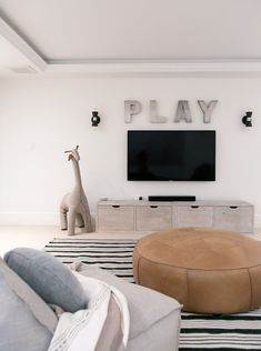 a giraffe is standing in front of a flat screen tv on the wall