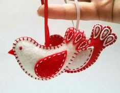 a red and white bird ornament hanging from a string in someone's hand