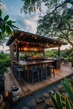 an outdoor bar with lots of stools and lights on the roof, surrounded by greenery