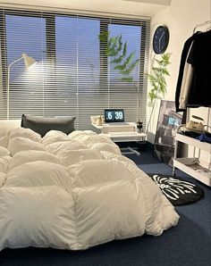 an unmade bed sitting next to a window in a room with blue carpet and white walls