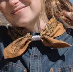 a close up of a woman wearing a denim jacket and a bow tie with her hair blowing in the wind