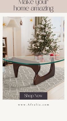 a glass coffee table sitting on top of a rug in front of a christmas tree