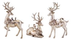 three statues of deers with antlers on their heads and one laying down next to it