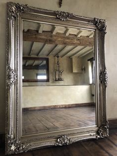 a large silver mirror sitting on top of a wooden floor