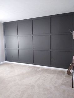 an empty room with gray paneled walls and white carpet, including a ladder in the foreground